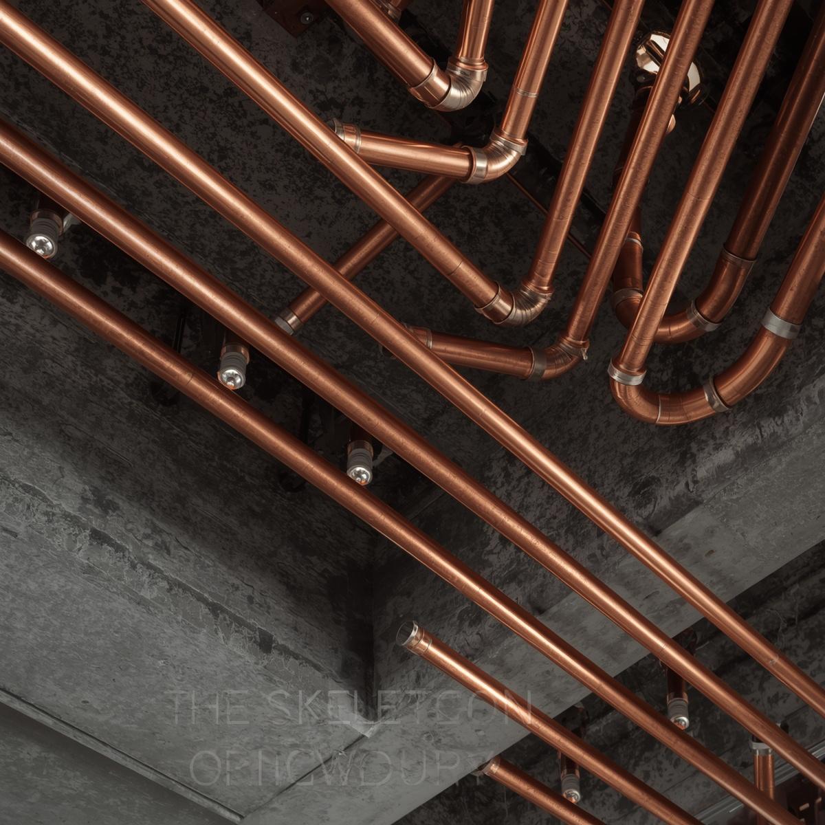 H&igrave;nh 2_ The Skeleton Art (Kiệt t&aacute;c Kỹ thuật Trần nh&agrave;)__Visual_ Chụp g&oacute;c hất từ dưới l&ecirc;n trần nh&agrave; (Low angle). Nền l&agrave; trần b&ecirc; t&ocirc;ng nguy&ecirc;n bản. Nổi bật l&agrave; những đường ống đồng (Coppe